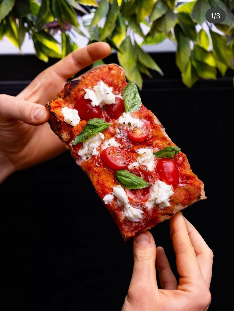 Hand holding a Roman-style pizza slab