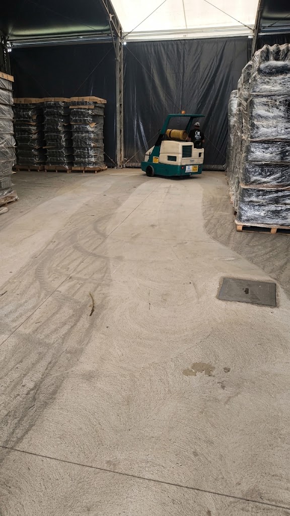 Varredeira industrial em galpão pós-obra removendo poeira e resíduos