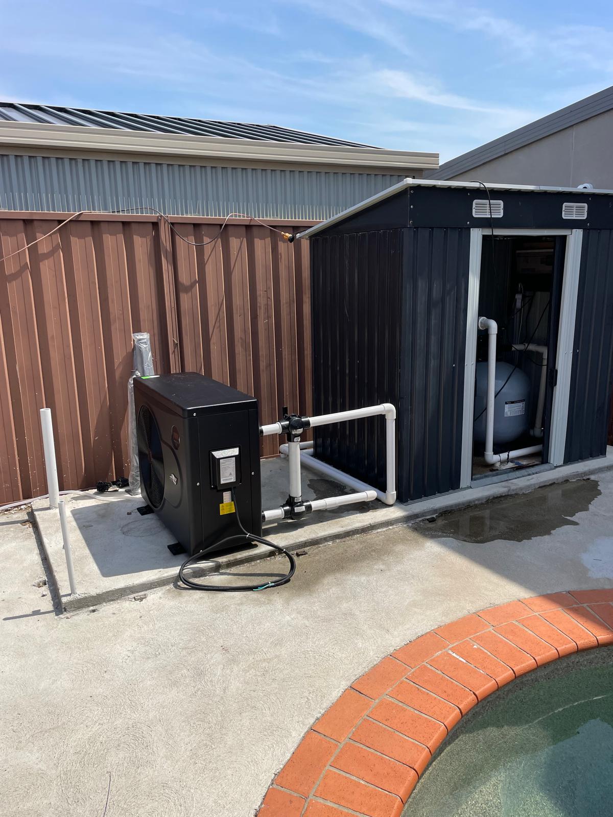 A newly installed black pool heat pump beside a Melbourne pool equipment area, installed by WW Pool & Spa